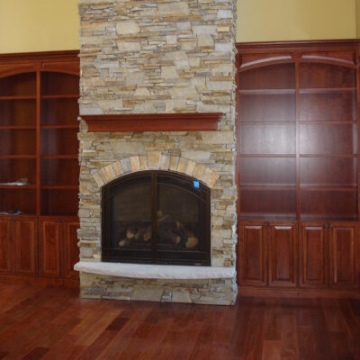 Limestone hearth on a fireplace with wood bookshelves and drystack ledgestone